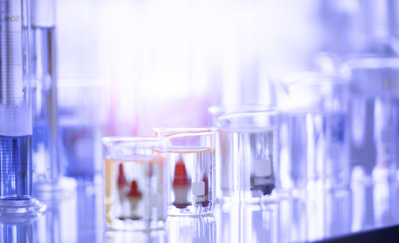 Menzura in merilne posodice različnih velikosti na mizi.