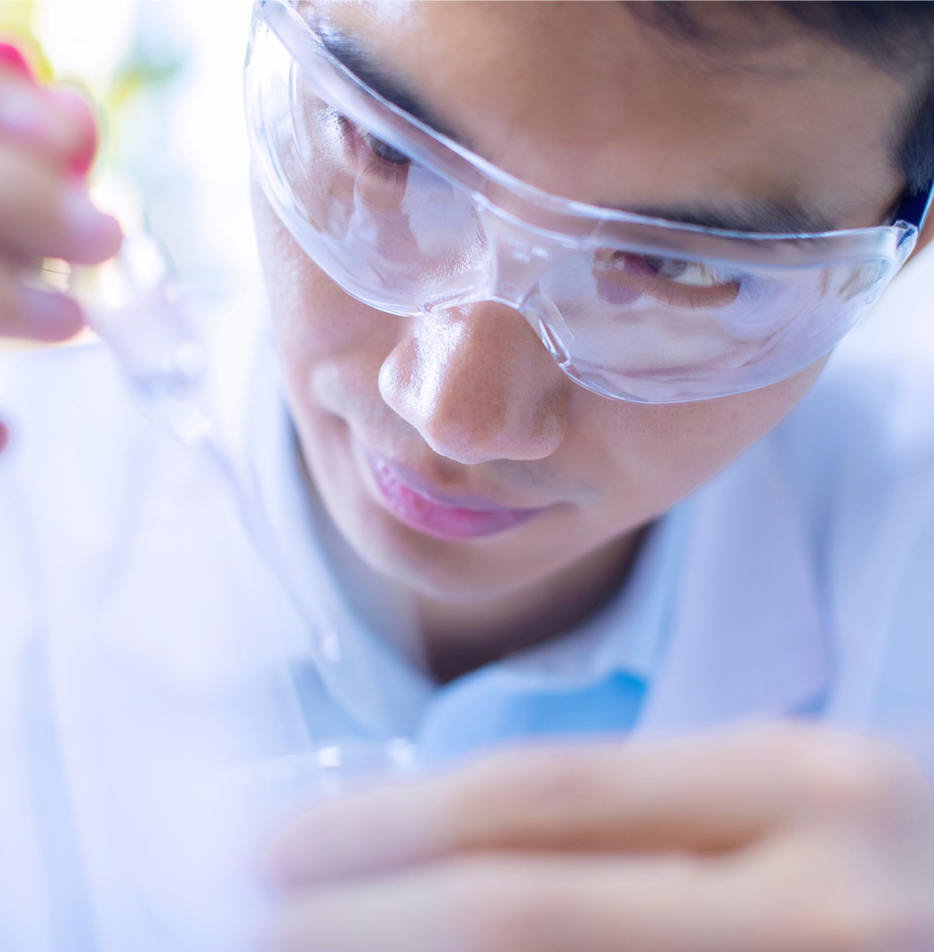 Delavec z zaščitnimi očali v laboratoriju. Drži kapalko.